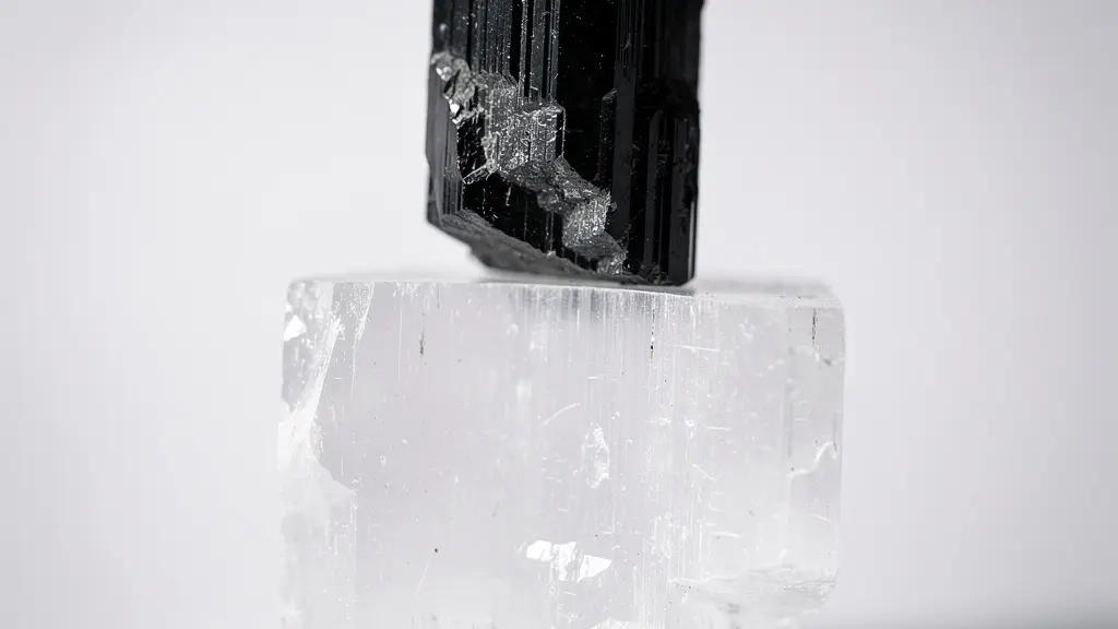 Placa de selenita blanca con turmalina negra descansando sobre ella bajo luz suave